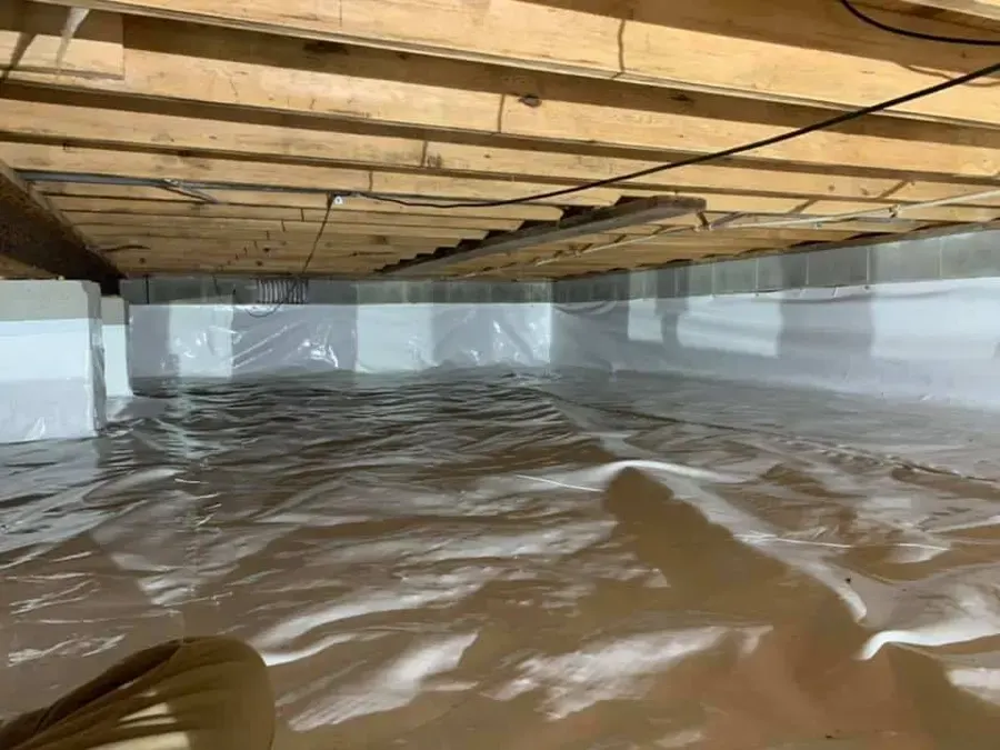Standing water on a crawl space vapor barrier under a Gwinnett home
